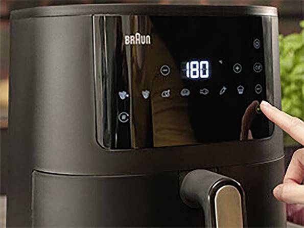 Una persona seleziona le impostazioni su un friggitrice ad aria Braun con un display digitale che mostra '180' gradi, sullo sfondo di una cucina.
