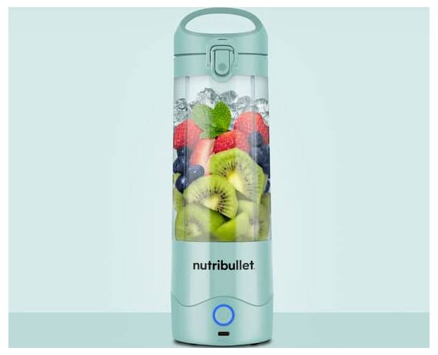 Un frullatore Nutribullet color turchese riempito con kiwi affettati, fragole, mirtilli e foglie di menta, posto su uno sfondo azzurro chiaro.