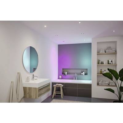 Bagno contemporaneo con uno specchio rotondo, lavabo sospeso, vasca da bagno e illuminazione d'ambiente. Mensole con asciugamani; una pianta aggiunge un tocco di verde.