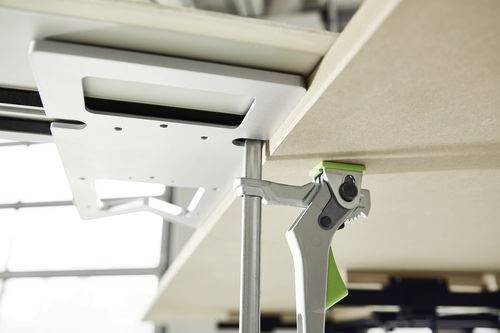 Una morsa che fissa una staffa metallica sotto una superficie in legno, probabilmente utilizzata per stabilizzare o unire parti in falegnameria o nell'assemblaggio di mobili.