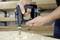 Una persona utilizza un trapano elettrico portatile per creare un foro su una superficie in legno. Trucioli di legno sono visibili intorno alla punta del trapano.