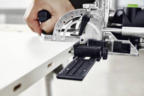Una persona utilizza un utensile specializzato per tagliare con precisione delle scanalature sul bordo di una tavola di legno, probabilmente per scopi di assemblaggio o di giunzione.