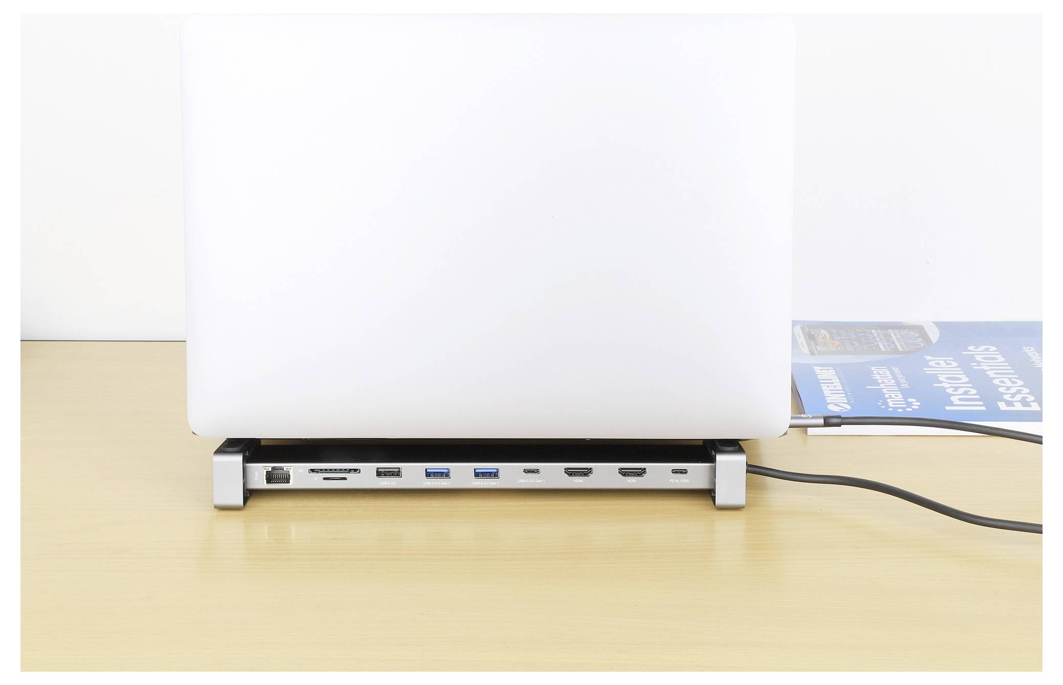 Un laptop è posizionato su una stazione di aggancio con più porte visibili, tra cui USB, HDMI ed Ethernet, su una scrivania in legno.