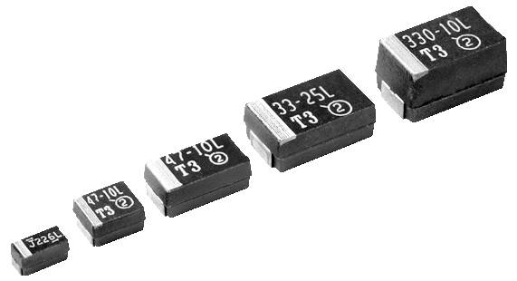 Cinque condensatori di diverse dimensioni con etichette numeriche che indicano la capacità e codici di serie, disposti in fila dal più piccolo al più grande.