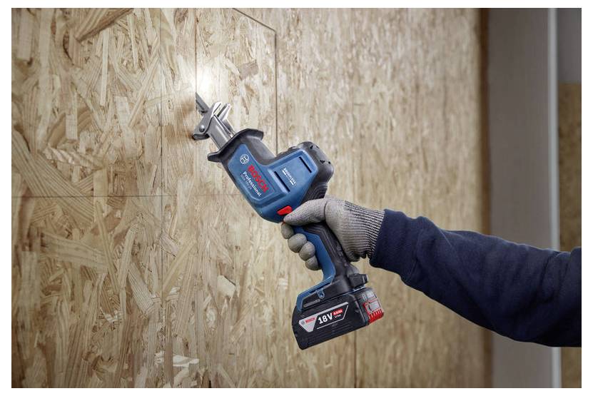 Una persona che indossa guanti utilizza una sega alternativa cordless per tagliare un pannello di legno. La sega è inclinata per un taglio preciso.