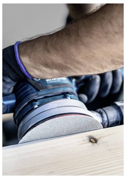 Una persona che utilizza una levigatrice elettrica su una superficie in legno, indossando guanti protettivi. L'attenzione è concentrata sul processo di levigatura e sull'utensile.