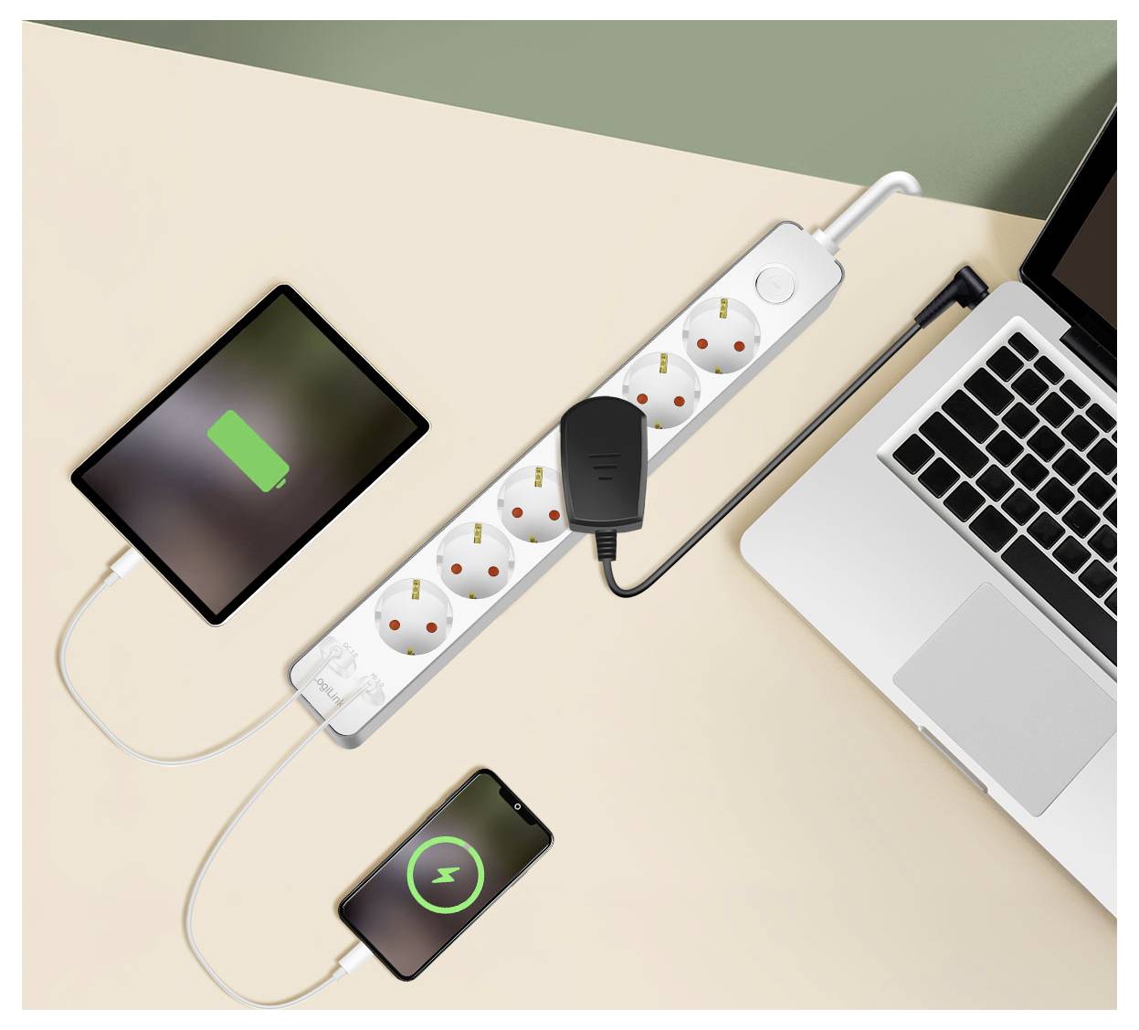 Una multipresa con più prese carica un tablet che mostra un'icona di batteria piena, uno smartphone e un laptop su una scrivania.