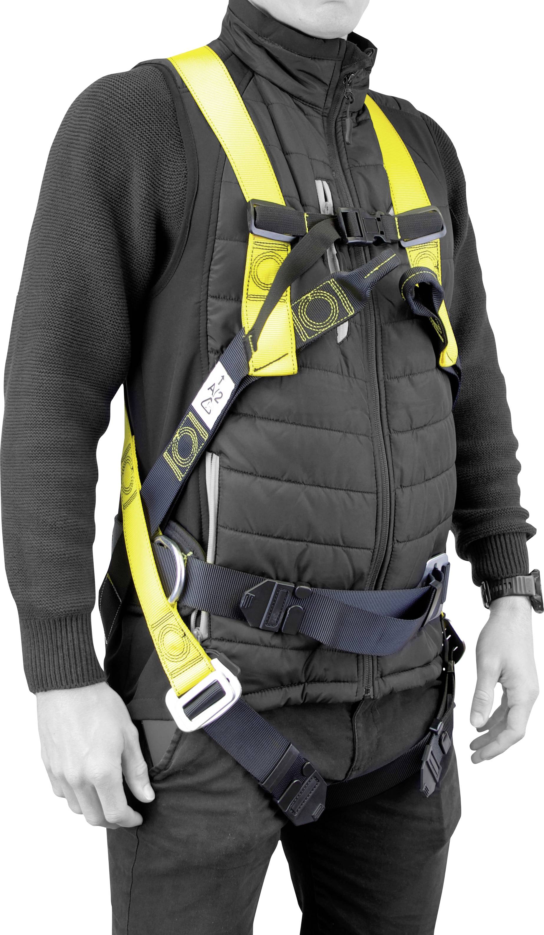 Una persona che indossa una giacca nera fa da modello per un'imbracatura di sicurezza gialla e nera, mettendo in evidenza le cinghie regolabili e le fibbie per un adattamento sicuro.