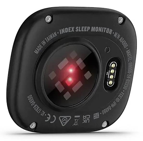 Un primo piano di un dispositivo elettronico nero con una luce LED rossa illuminata, etichettato 'Index Sleep Monitor', che indica la capacità di monitorare il sonno.