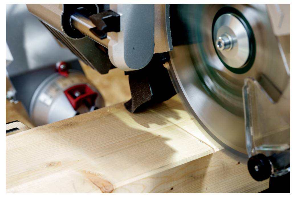 Una sega circolare che taglia un'asse di legno, con sfocatura del movimento visibile sulla lama, che indica un'alta velocità.