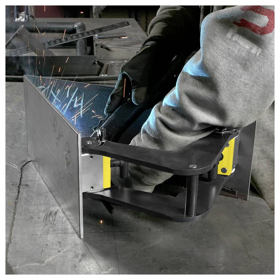 Una persona che indossa guanti sta saldando pezzi di metallo insieme, con scintille che volano. L'ambiente di lavoro suggerisce un laboratorio metallurgico.