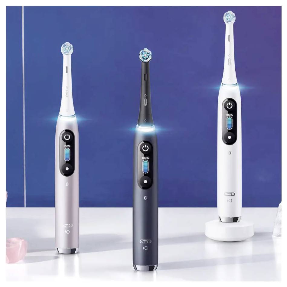 Tre spazzolini da denti elettrici in rosa, nero e bianco su uno sfondo blu, che evidenziano il loro design elegante e i pulsanti di accensione illuminati.