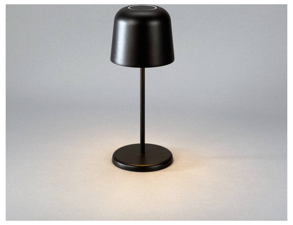 Una lampada da tavolo moderna e elegante, in nero, con un paralume e base cilindrici, che proietta una luce soffusa su una superficie neutra.