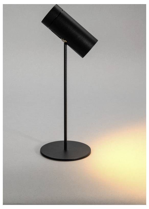 Una lampada da scrivania moderna in nero che proietta una luce circolare calda su una superficie grigia, che mostra un design minimalista con una testa cilindrica e un supporto sottile.