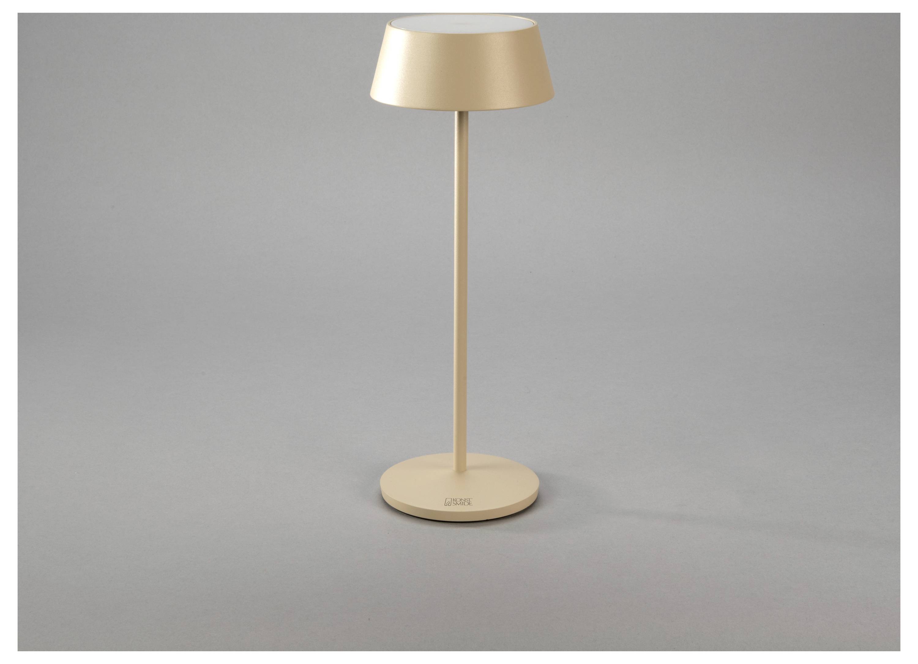 Una lampada da tavolo elegante e moderna, con base e paralume rotondi, in un colore beige chiaro, poggiata su una superficie grigia.