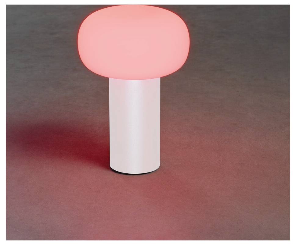 Una lampada rosa luminosa con una base cilindrica bianca e parte superiore arrotondata emette una luce soffusa su una superficie scura.