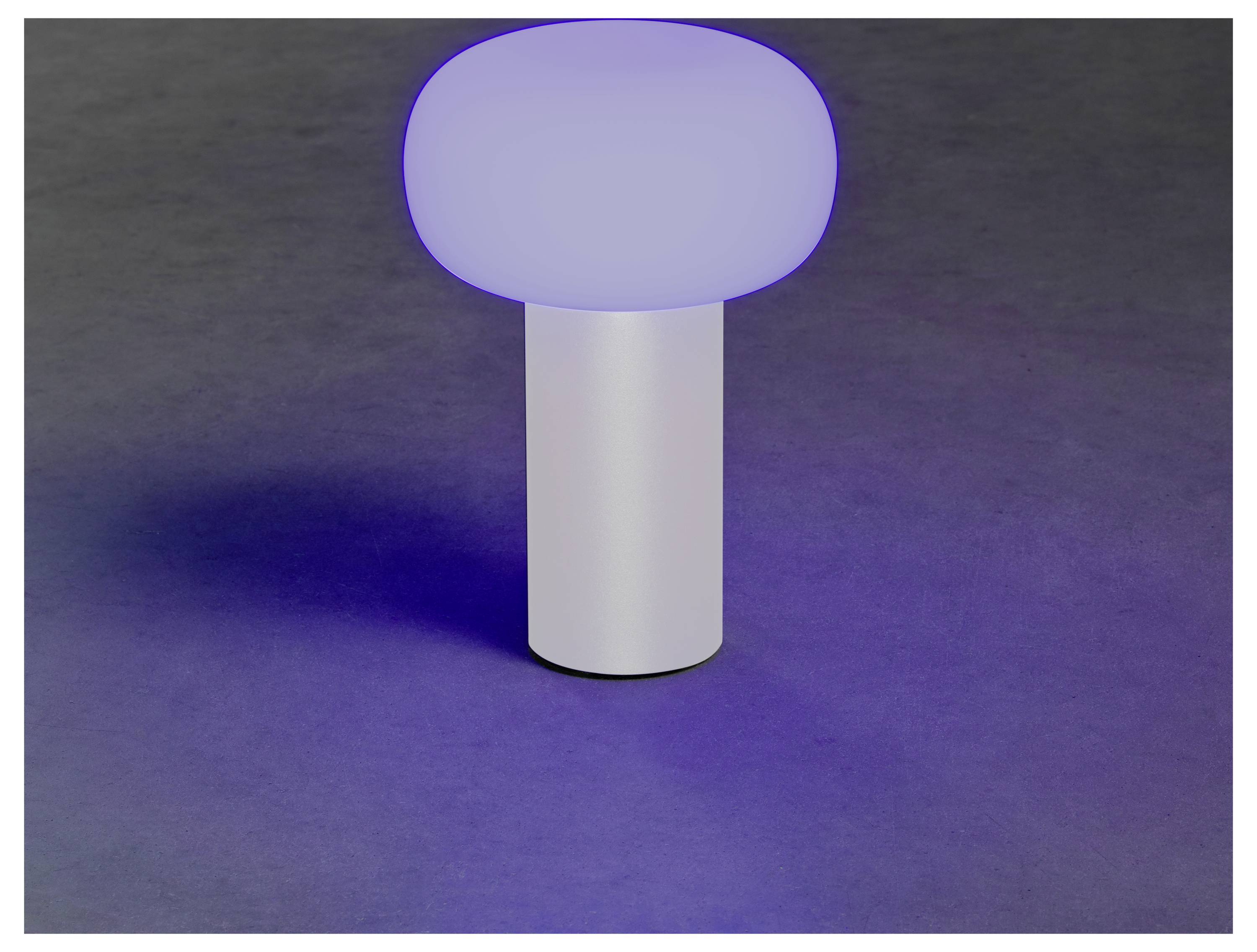 Una lampada moderna e minimalista con base cilindrica emana un bagliore blu soft su una superficie scura.