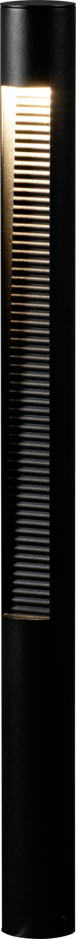 Una lampada alta e cilindrica di colore nero, con listelli verticali, emette una luce calda dalla sezione superiore, creando un bagliore soffice in un design moderno.