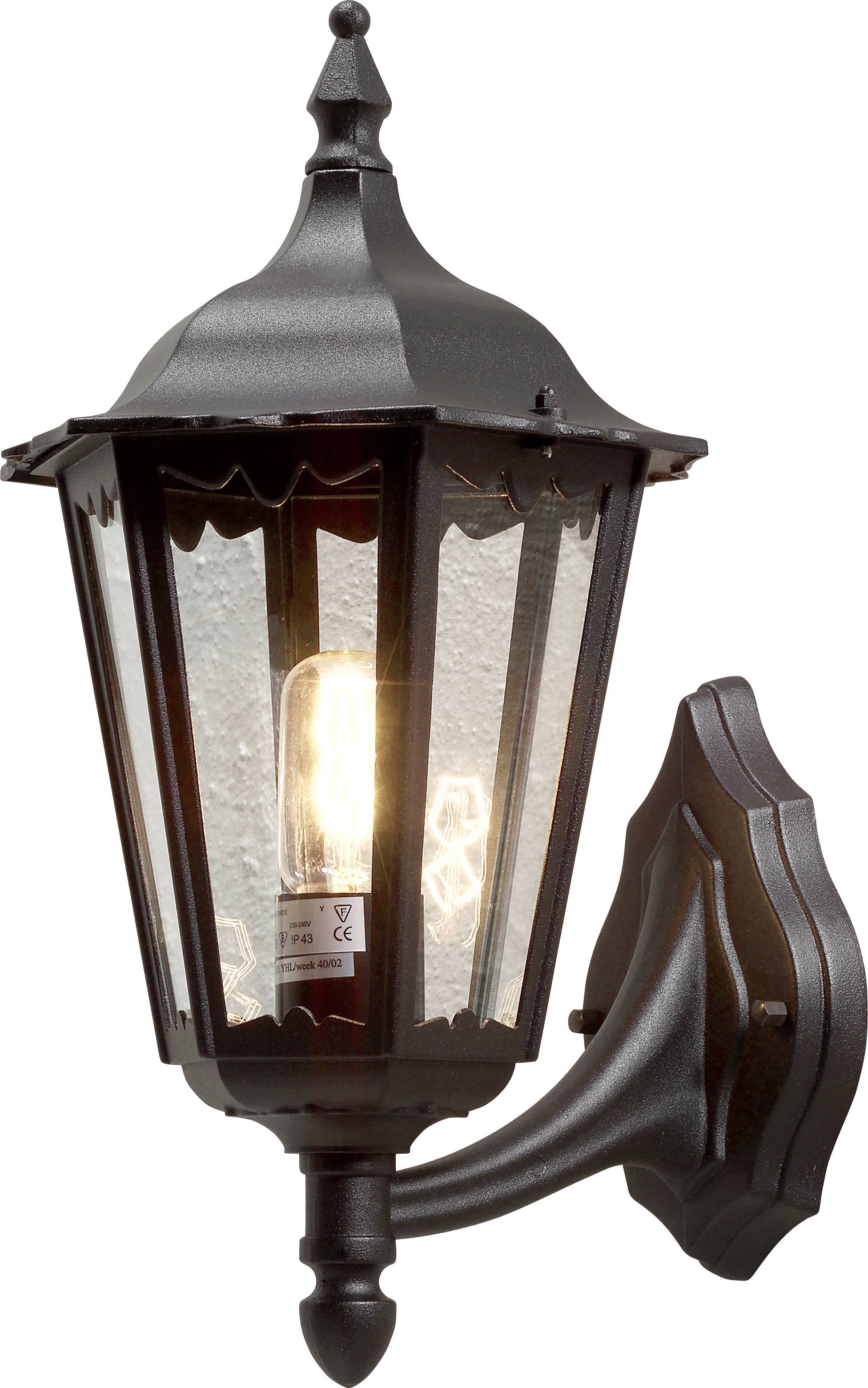 Una lanterna da esterno vintage in nero, con pannelli di vetro trasparenti, fissata al muro di una casa, illumina con una lampadina che emana un bagliore all'interno.