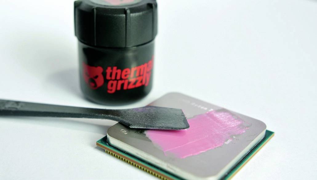 Applicazione di pasta termica da un contenitore 'Thermal Grizzly' su un processore per computer utilizzando una spatola.
