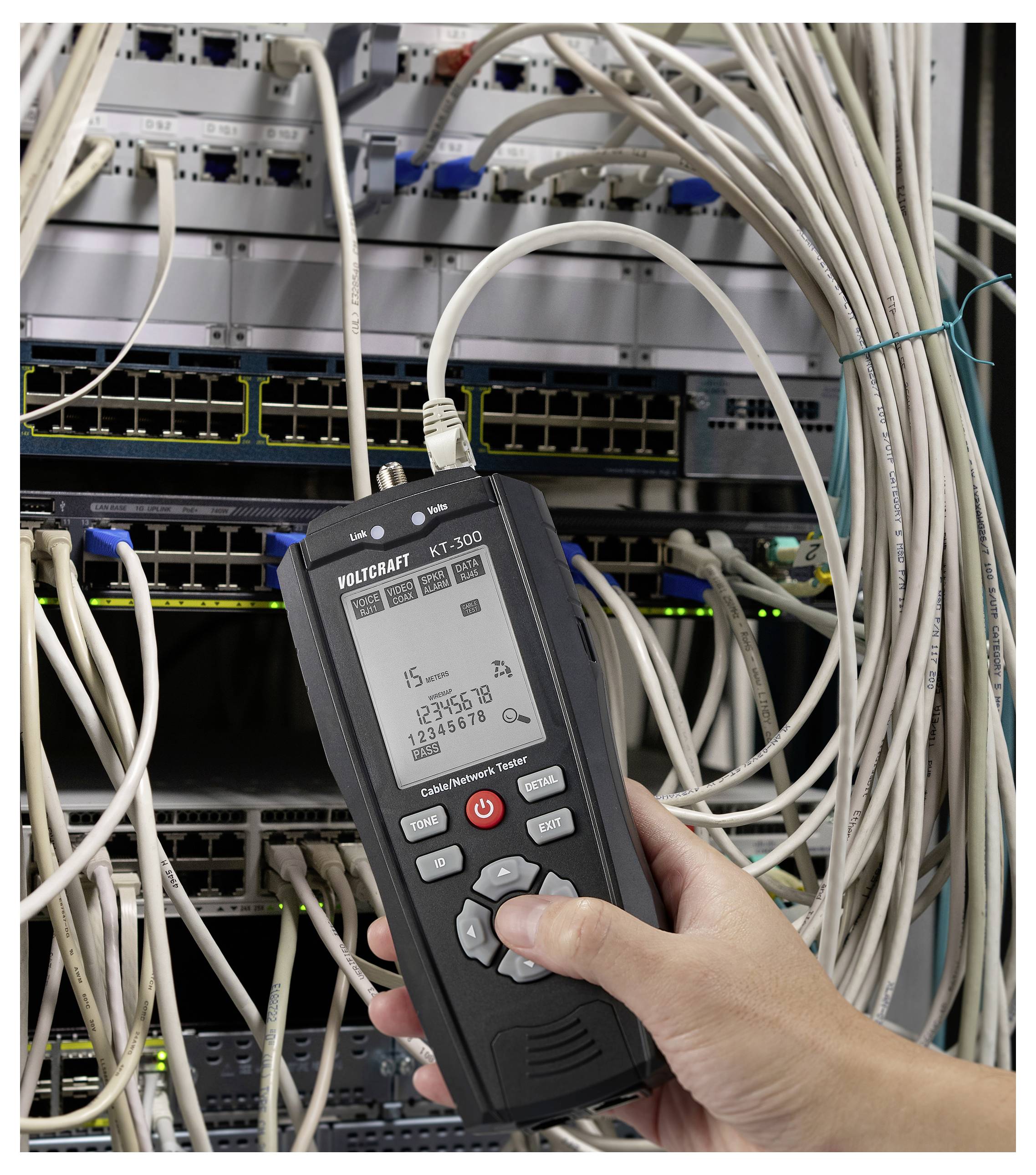 Una persona tiene un tester di cavi di rete accanto a un rack di server, verificando la connettività. Lo schermo visualizza dati relativi alla rete e numeri.