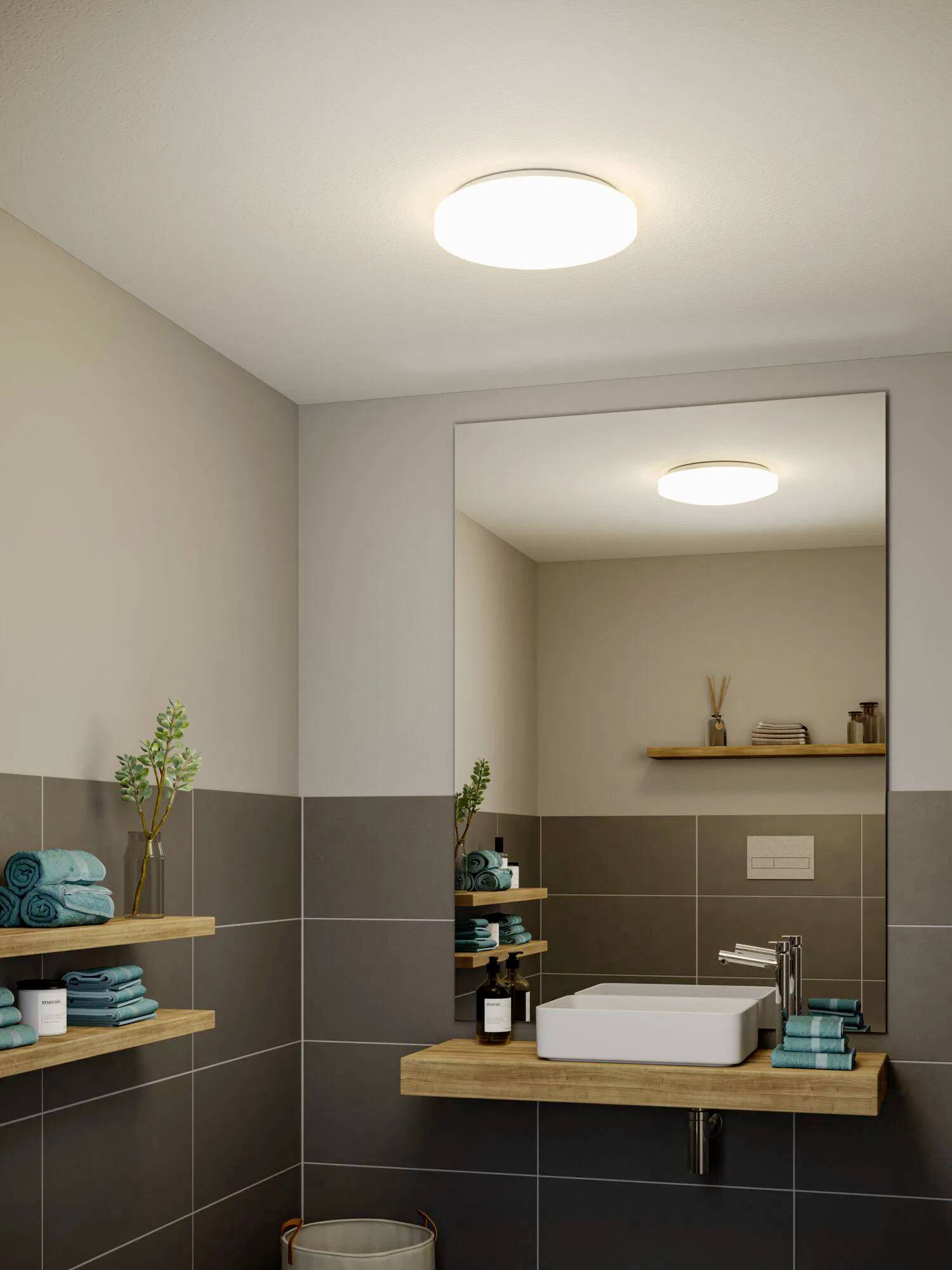 Un bagno moderno con un lavabo elegante, mensole in legno che ospitano asciugamani e articoli da bagno, e un lampadario rotondo che illumina lo spazio.