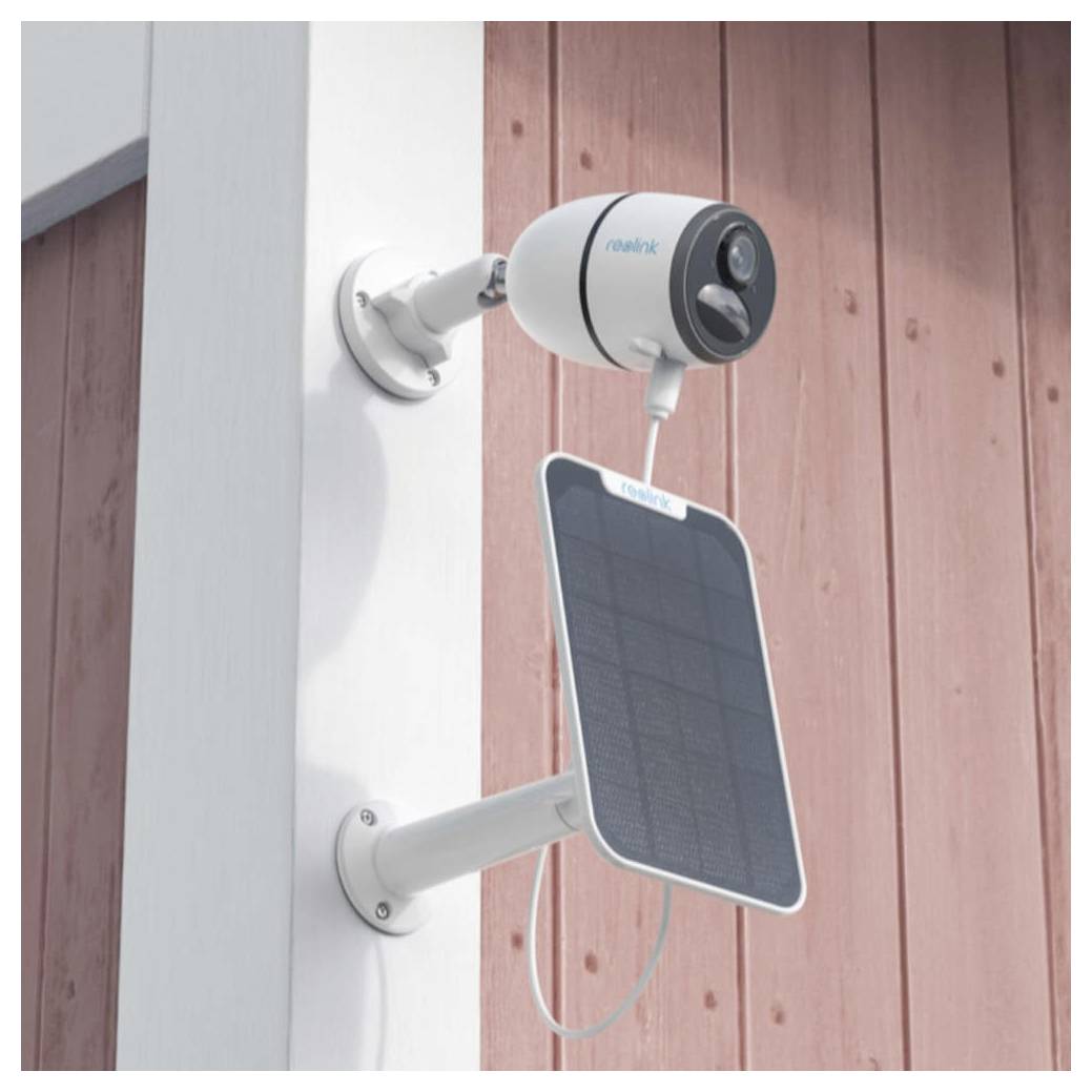 Una telecamera di sicurezza bianca con il marchio 'realink' e un pannello solare attaccato sotto, montata su una parete di legno, che guarda verso l'esterno.
