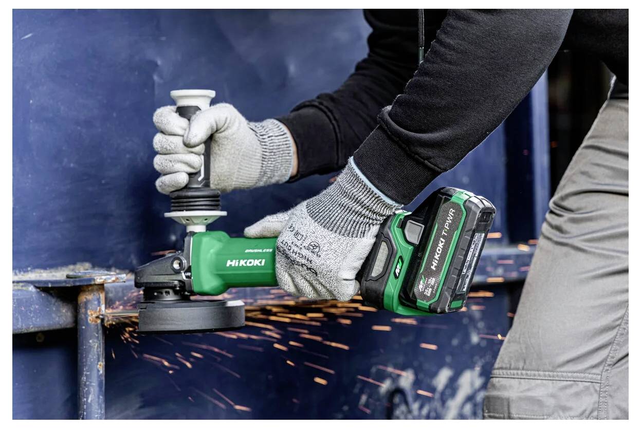 Persona che usa un utensile elettrico Hitachi per levigare il metallo, indossando guanti e facendo schizzare scintille.