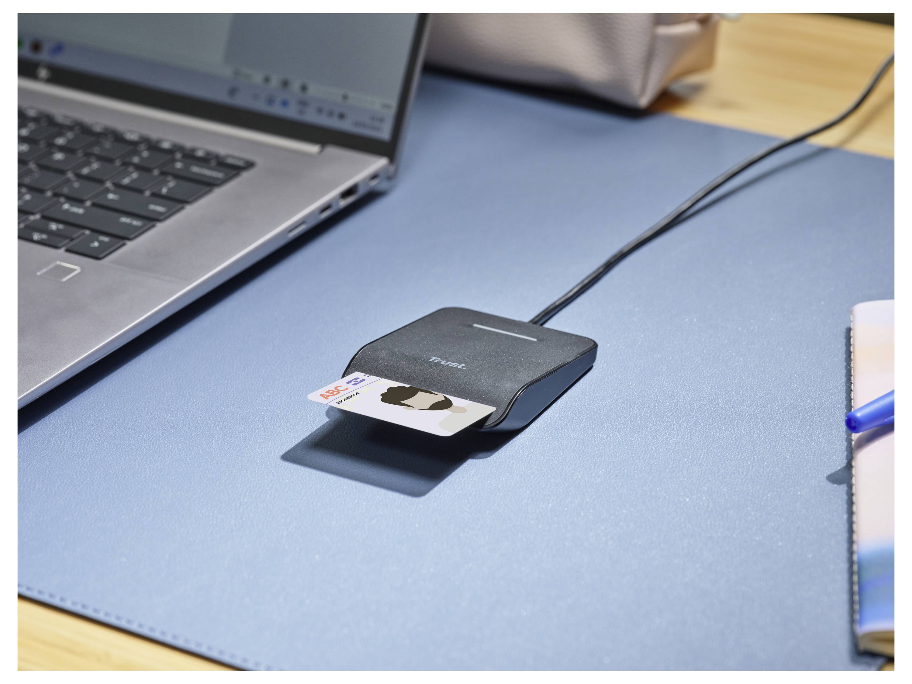 Una carta di credito viene inserita in un lettore di carte collegato a un laptop, posizionato su una scrivania con un tappetino blu, che indica l'elaborazione di un pagamento online.