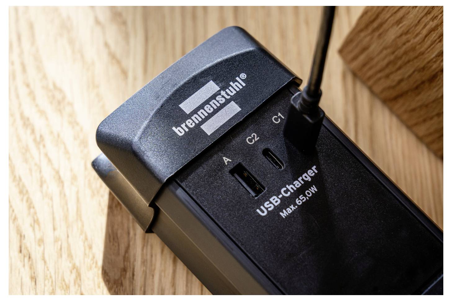 Un primo piano di un'unità caricabatterie USB con etichetta 'brennenstuhl', che mostra le porte A, C2 e C1, con un dispositivo collegato alla porta C1.