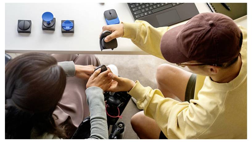 Due persone sedute a un tavolo esaminano diversi prototipi di mouse per computer, illustrando collaborazione ed esplorazione del design.