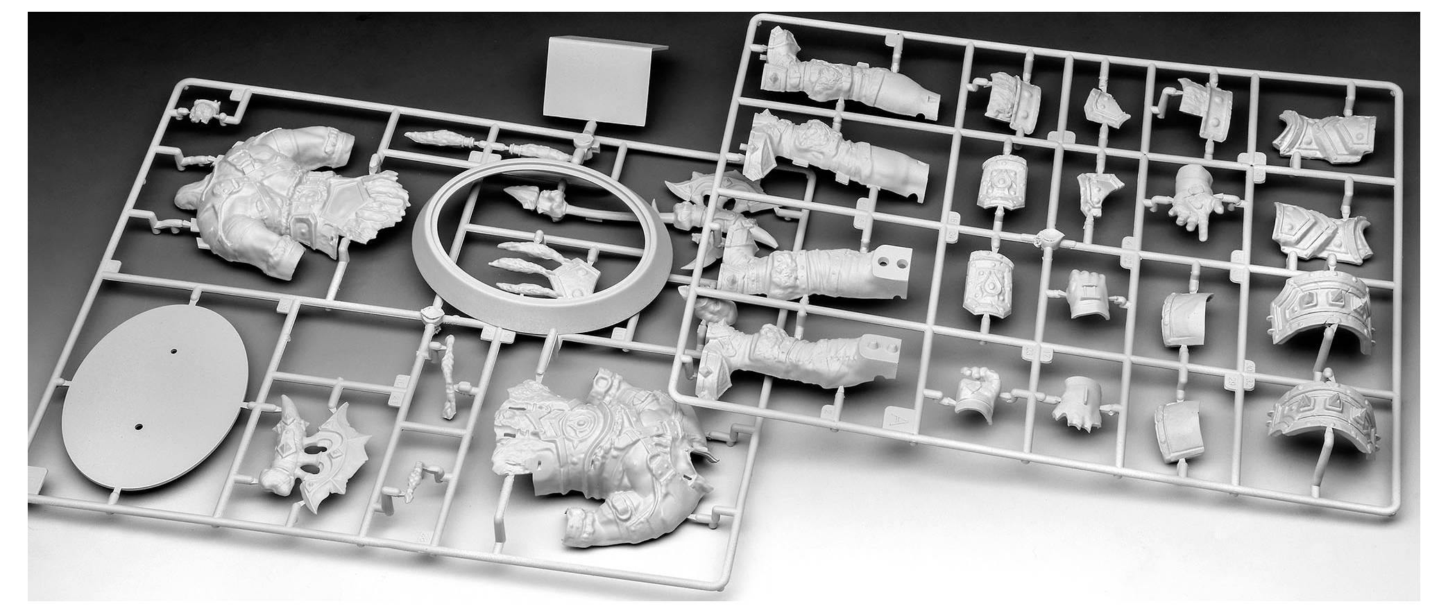 Kit di modellismo in plastica con traverse contenenti vari pezzi per l'assemblaggio, compresi componenti di armatura e parti di armi. I pezzi sono disposti su due griglie rettangolari.
