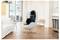 Un cuscinetto per seduta massaggiante dal design elegante è posizionato su una moderna sedia girevole bianca in un ambiente living contemporaneo e luminoso.