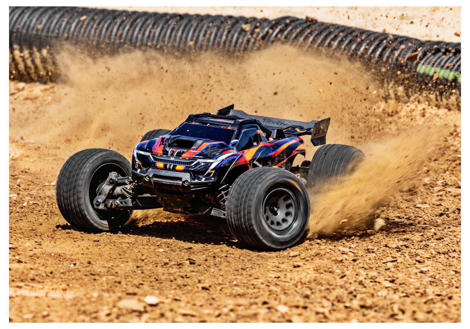 Un'auto radiocomandata sfreccia attraverso una pista sterrata, sollevando polvere, mettendo in risalto il suo design robusto e le sue capacità ad alta velocità.