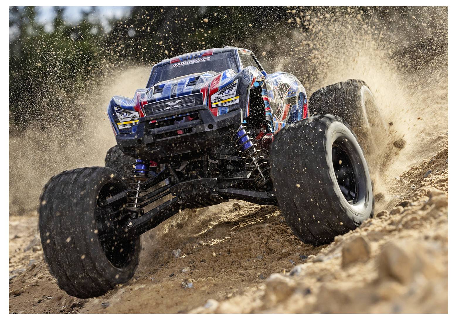 Un monster truck radiocomandato che corre su una pista sterrata, sollevando polvere e detriti mentre sfreccia attraverso il terreno roccioso.