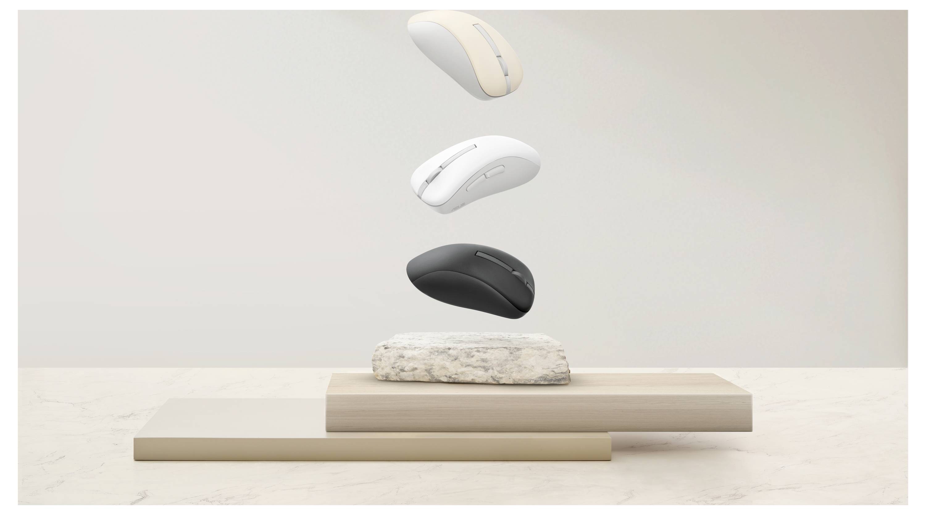 Mouse wireless per computer in beige, bianco e nero che fluttuano sopra superfici impilate di colore beige e pietra, che illustrano la varietà di colori.