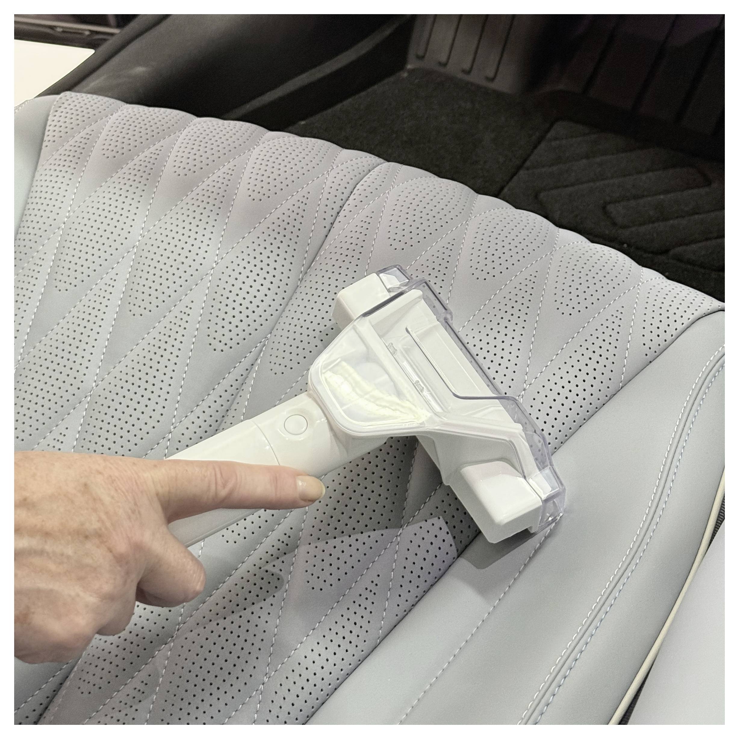 Una persona dimostra l'uso di un aspirapolvere portatile su un sedile dell'auto, illustrando la sua efficacia nella rimozione dello sporco dai rivestimenti.