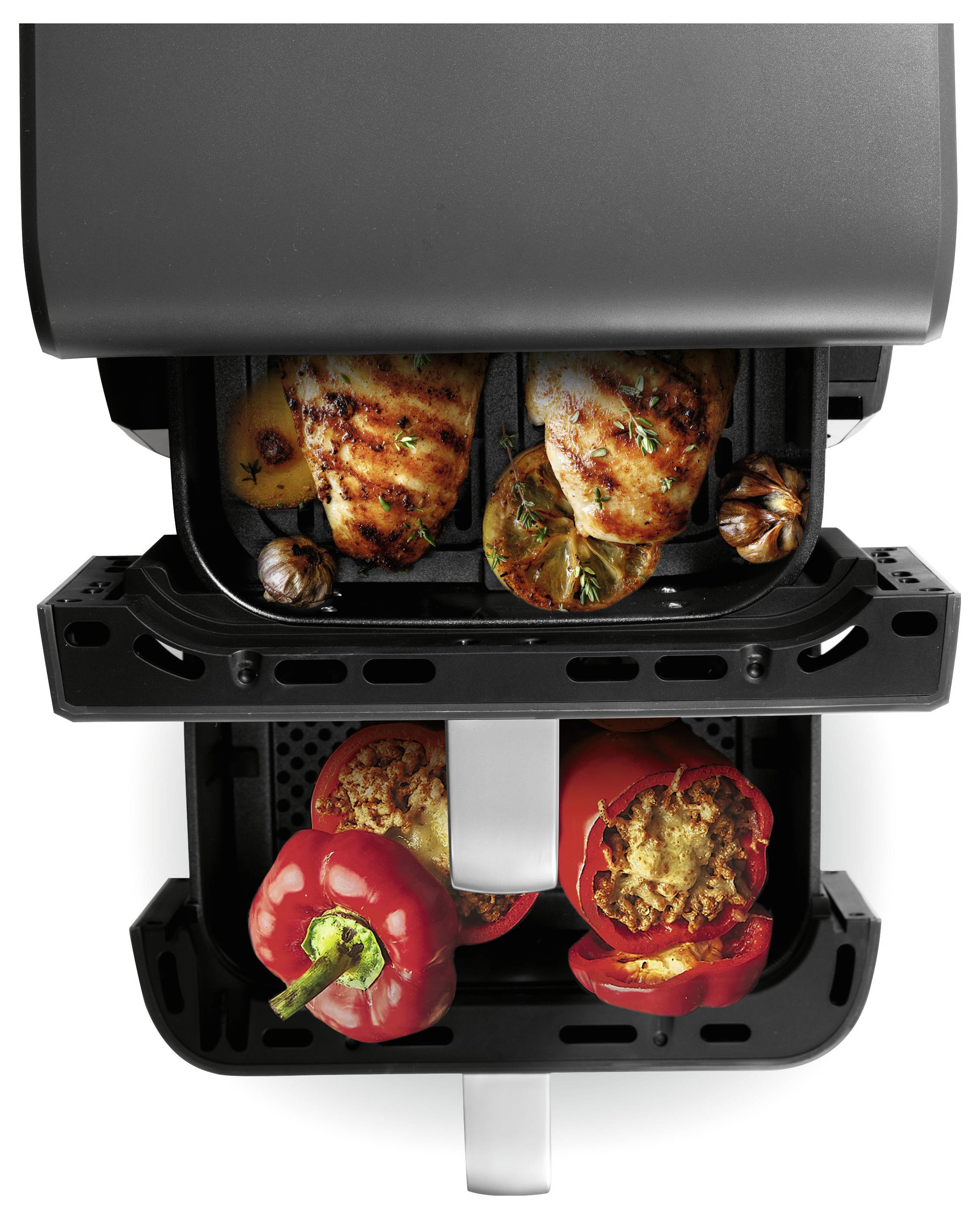 Friggitrice ad aria doppia che cuoce cosce di pollo e verdure in un comparto, e peperoni ripieni nell'altro, vista dall'alto.
