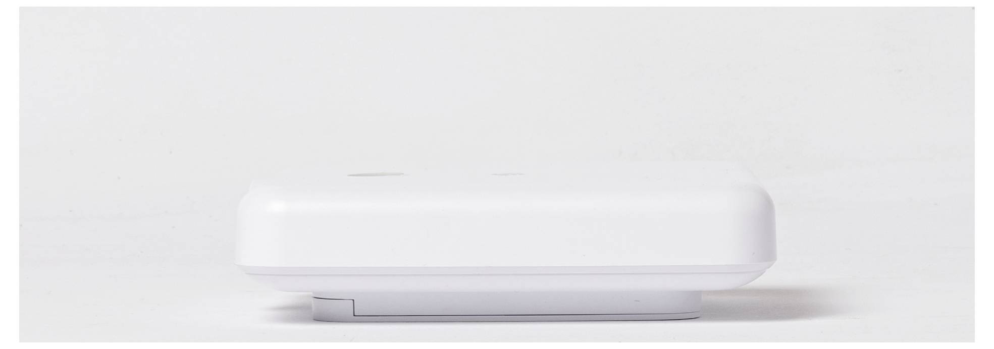 Un oggetto rettangolare bianco con bordi arrotondati, visto di lato, su uno sfondo neutro.