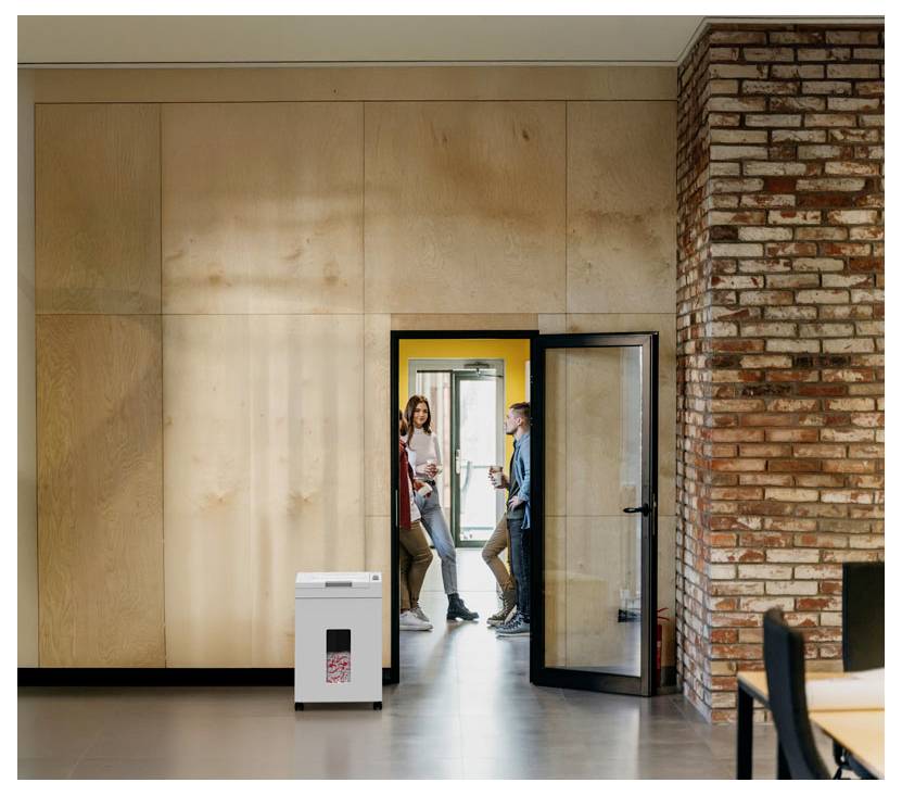 Un piccolo gruppo di persone che chiacchierano in modo informale vicino a un ingresso in un ufficio moderno, con un muro di mattoni e pannelli in legno visibili.