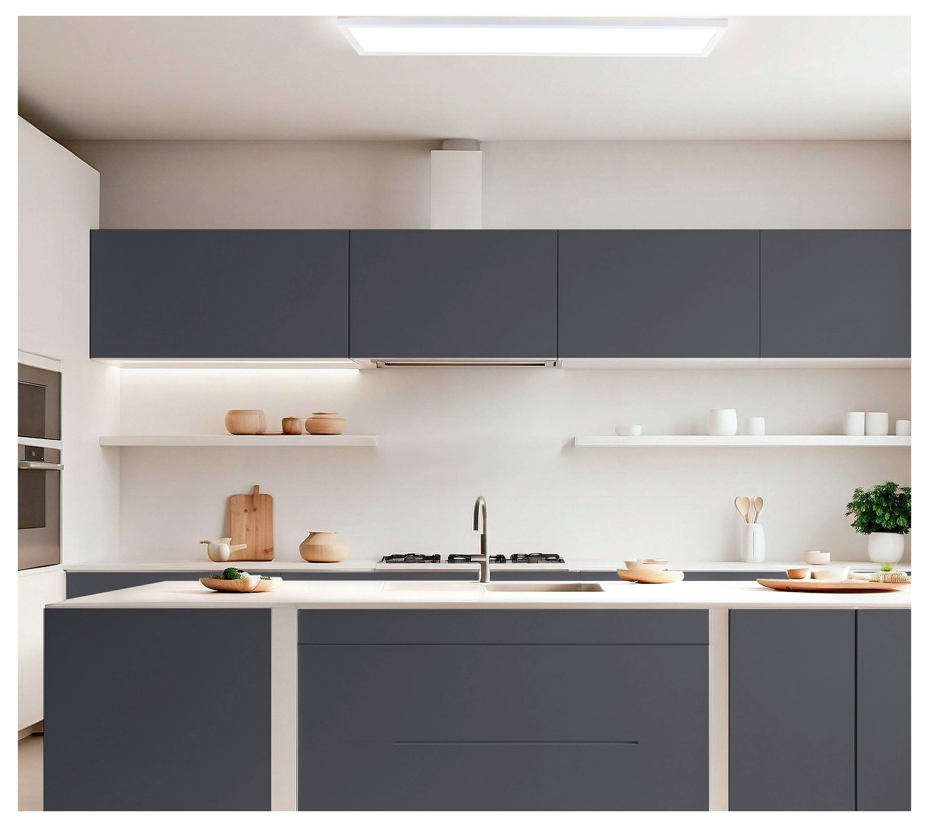 Una cucina moderna con armadietti scuri, piani di lavoro chiari e elettrodomestici in acciaio inossidabile. L'arredamento minimalista include piante e utensili in legno.