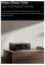 Un proiettore dal design elegante è posato su una superficie in legno, illuminato dalla luce naturale. Il testo mette in evidenza il suo pannello in cristallo radiante di alta qualità.