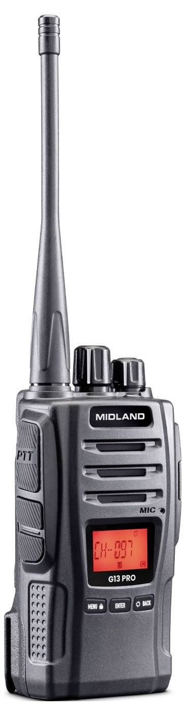 Una persona in mimetica militare con una radio agganciata alla cintura sta in piedi in un edificio industriale con la luce del sole che filtra attraverso le finestre.