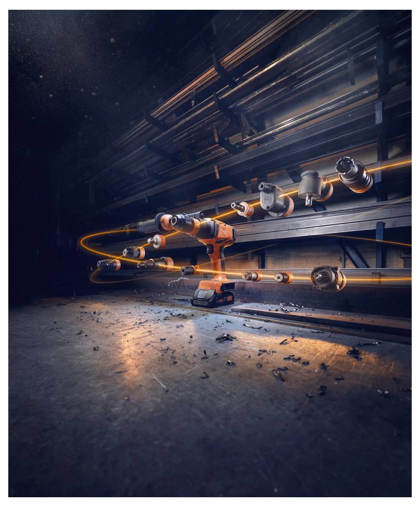 Una punta da trapano con molteplici accessori che galleggiano intorno ad essa, circondata da una scia di luce arancione, in un drammatico ambiente di officina.