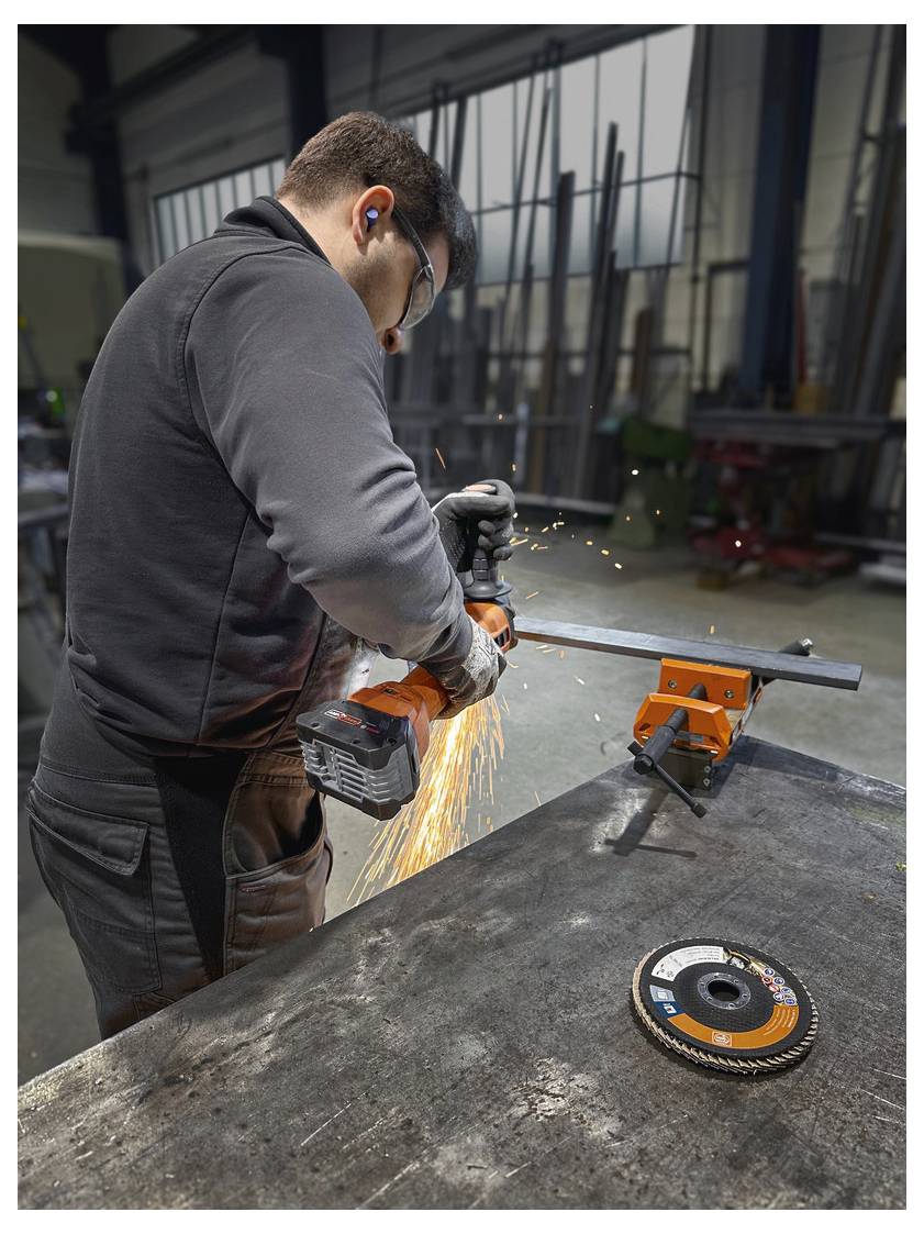 'Uomo che utilizza un'smerigliatrice portatile su metallo, producendo scintille, in un laboratorio industriale. Vengono utilizzati dispositivi di protezione, inclusa la protezione dell'udito.'