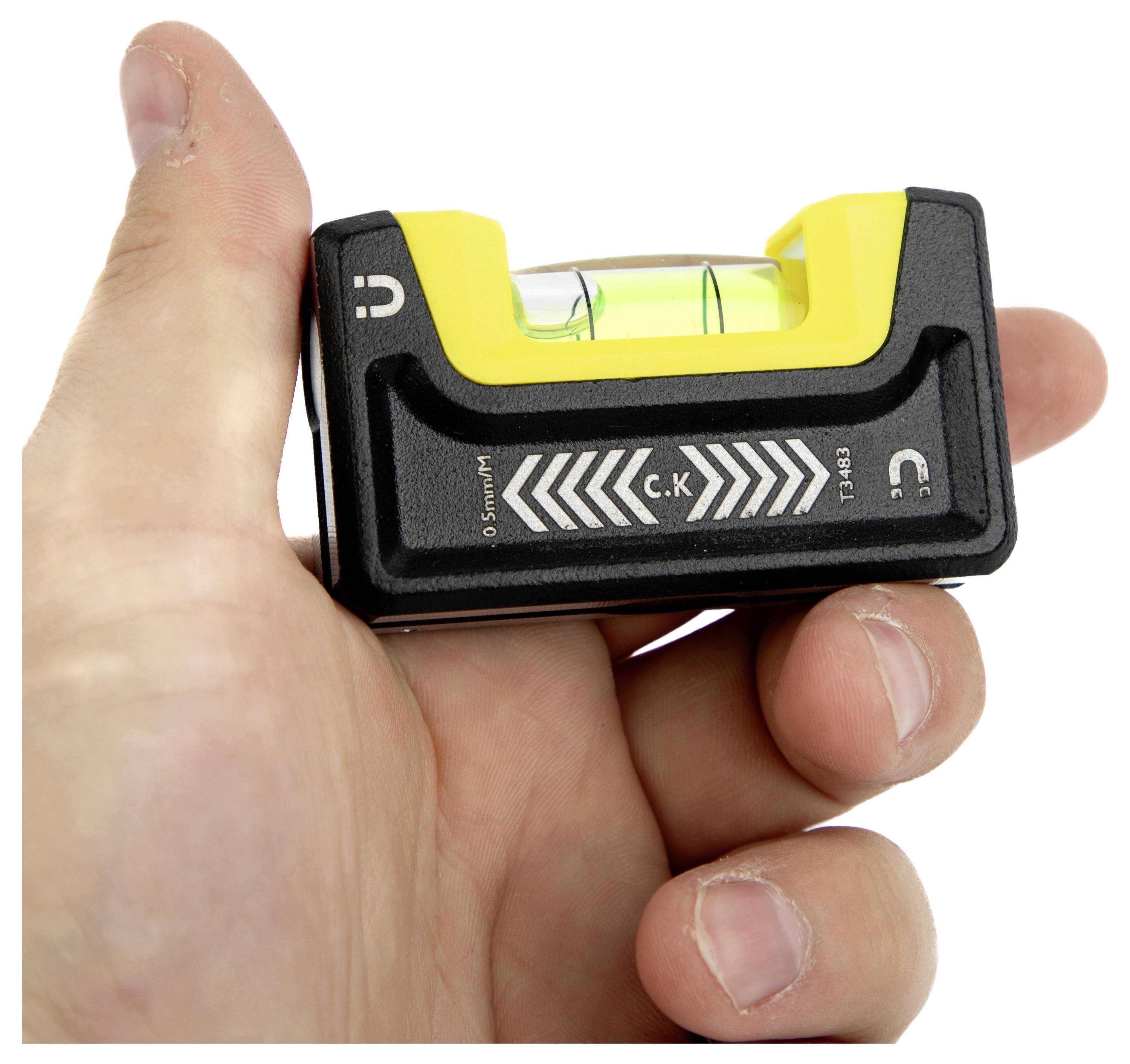 Una mano che tiene uno strumento piccolo di livella a spirito giallo e nero con una bolla visibile nella fiala riempita di liquido per misurare l'allineamento orizzontale.