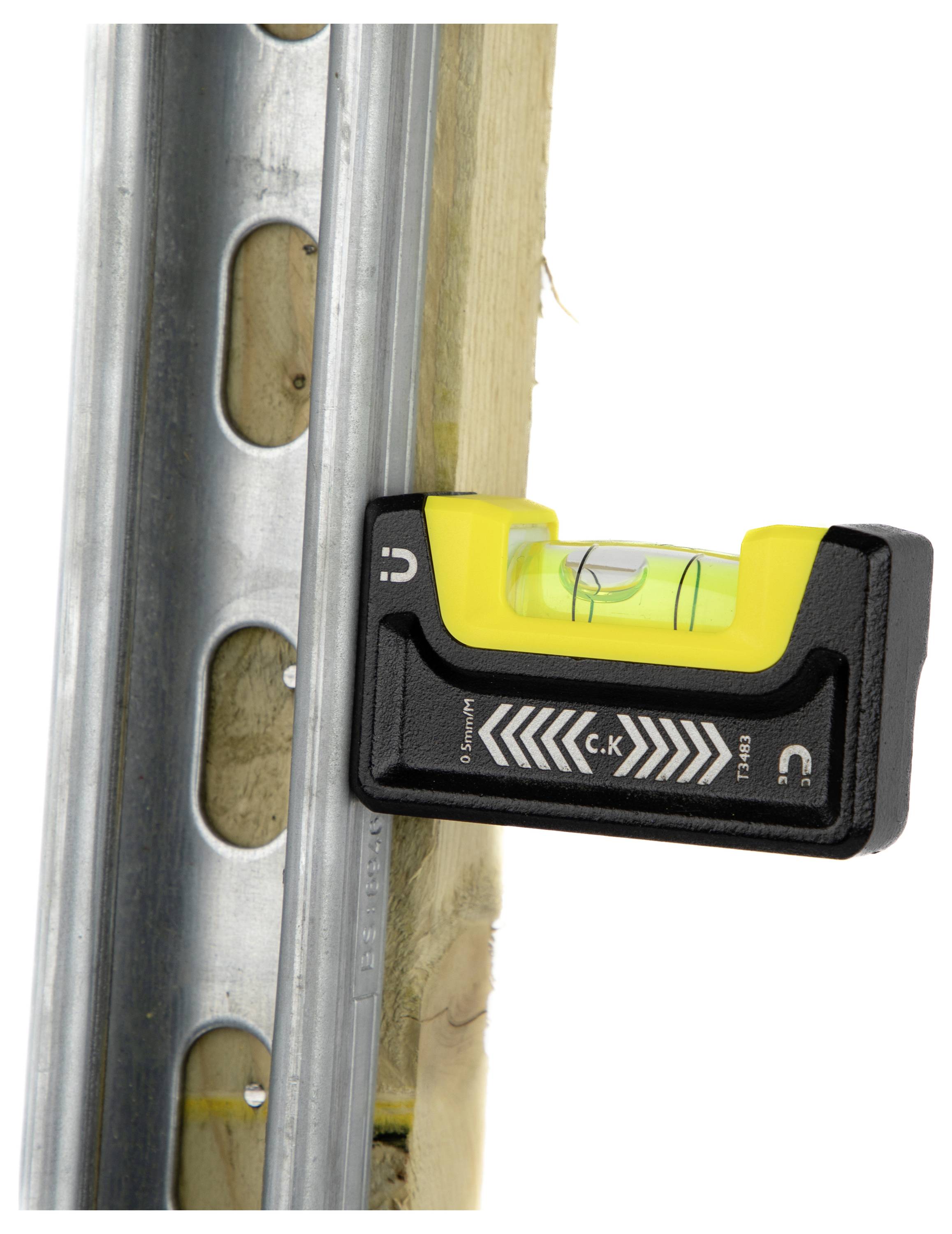 Un piccolo livello a bolla magneticamente fissato a una trave metallica mostra una bolla centrata, indicando che la trave è perfettamente in livello verticale.