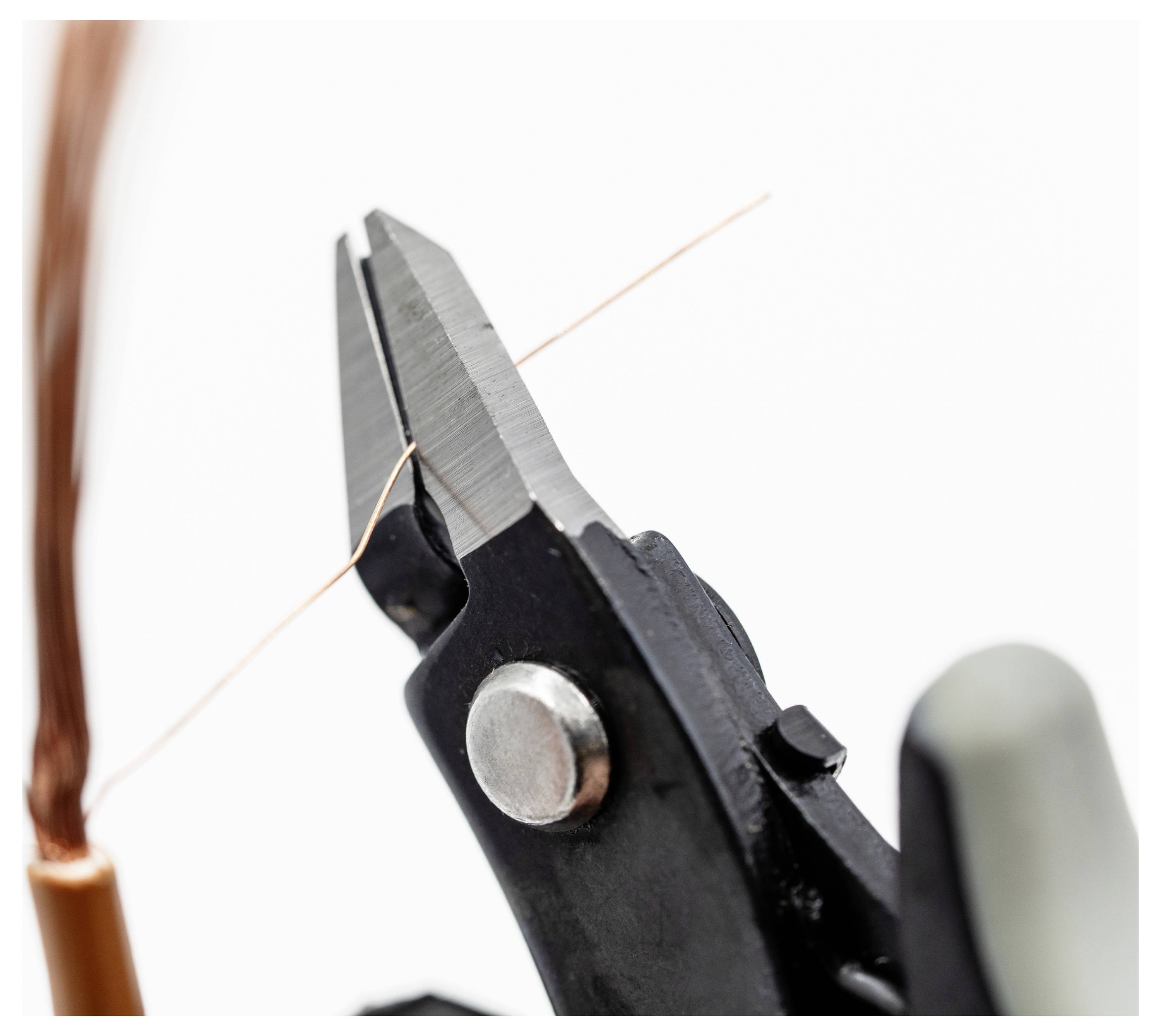 Primo piano di forbici per tagliare i fili che tagliano un sottile filo di rame, evidenziando la precisione dello strumento su uno sfondo neutro.