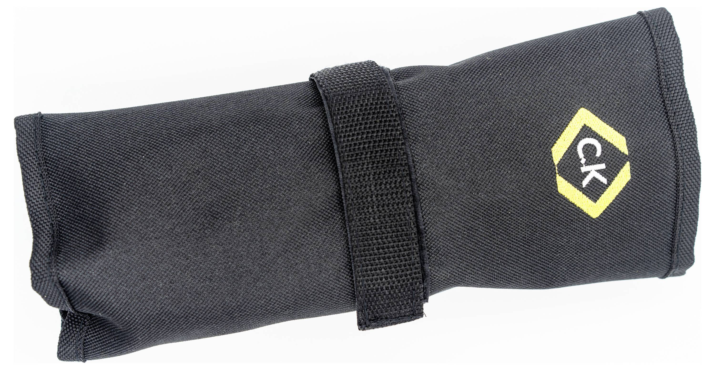 Un rotolo di tessuto nero per attrezzi con un logo esagonale giallo e le lettere 'CK', assicurato con una cinghia in velcro.