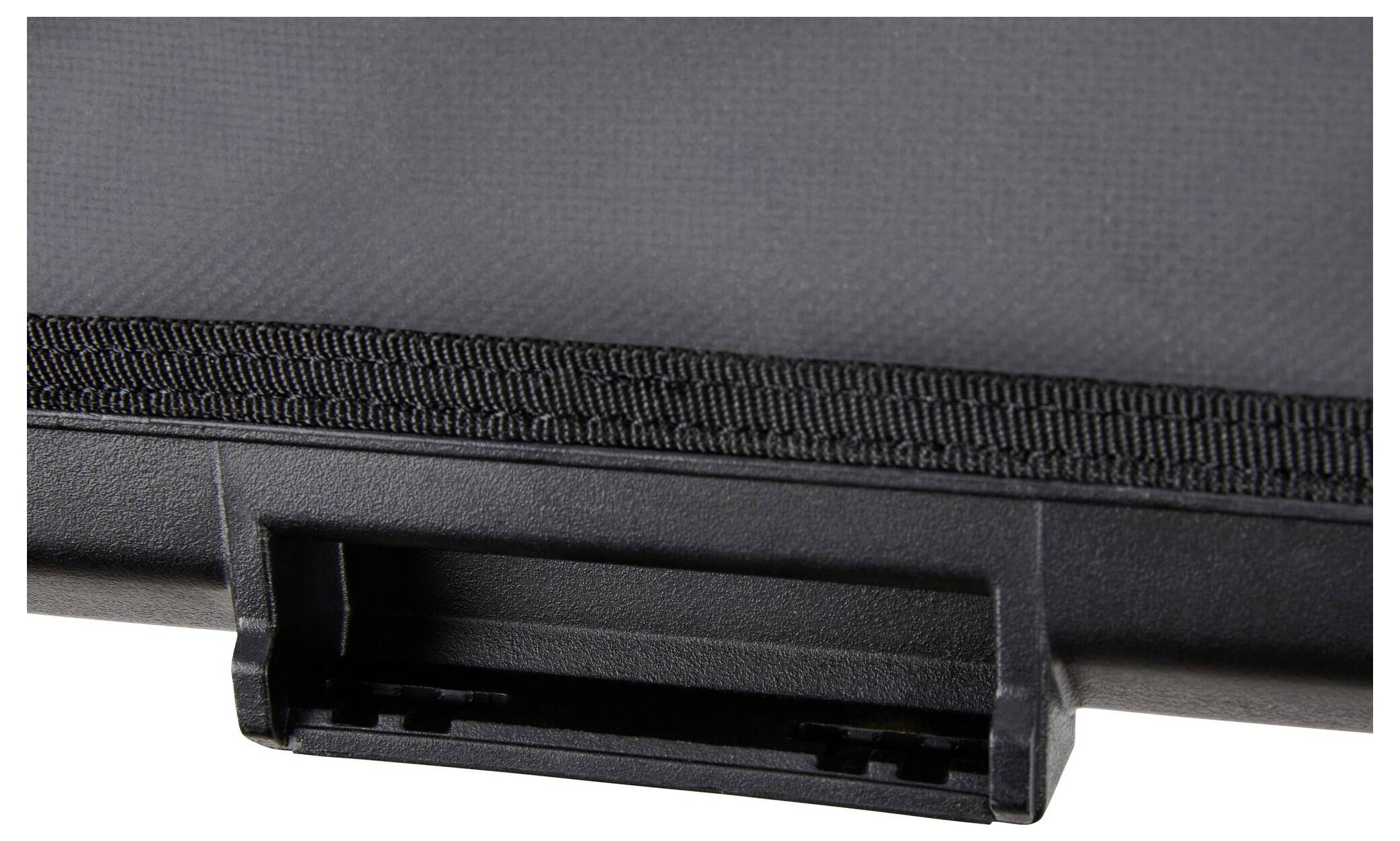 Primo piano di un tessuto nero o materiale strutturato con un bordo in plastica o gomma e un piccolo manico rettangolare o fermo nella parte inferiore.